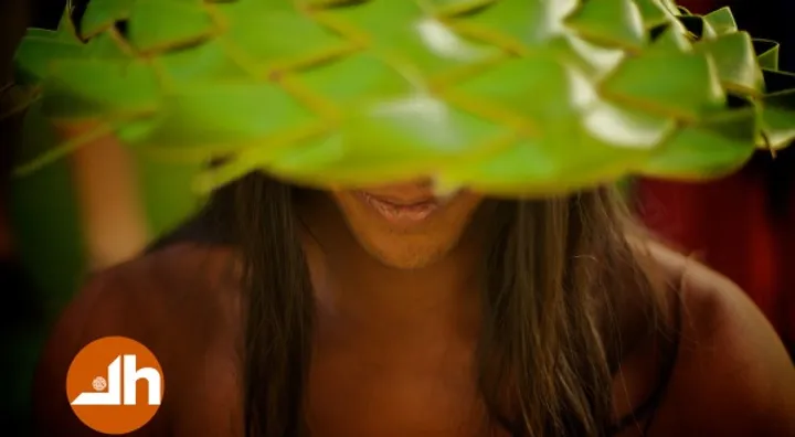 Woman smiling under a woven palm-leaf hat, photograph by Casey Templeton.